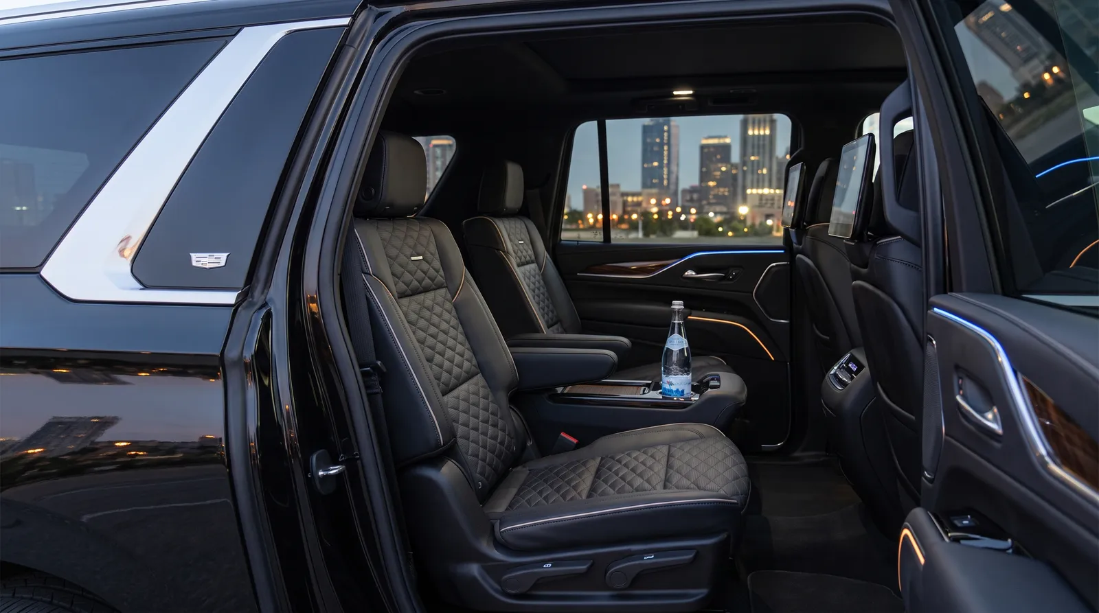 Quilted black leather rear seats with ambient lighting inside a luxury black sedan