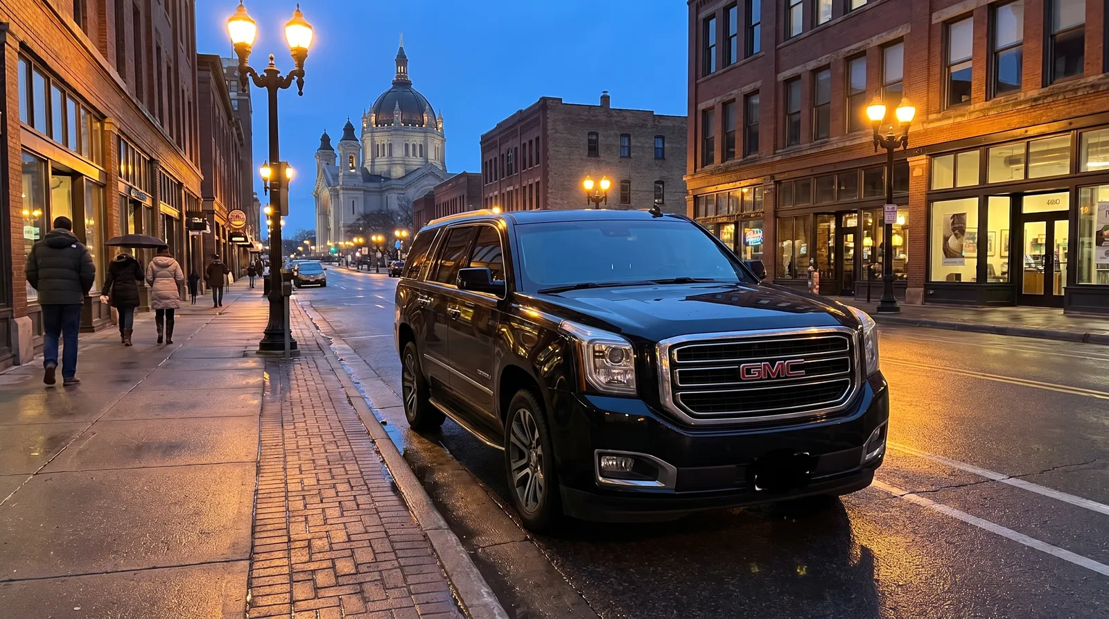 Black GMC Yukon Denali parked on a downtown Saint Paul street at dusk with the cathedral on the hill behind