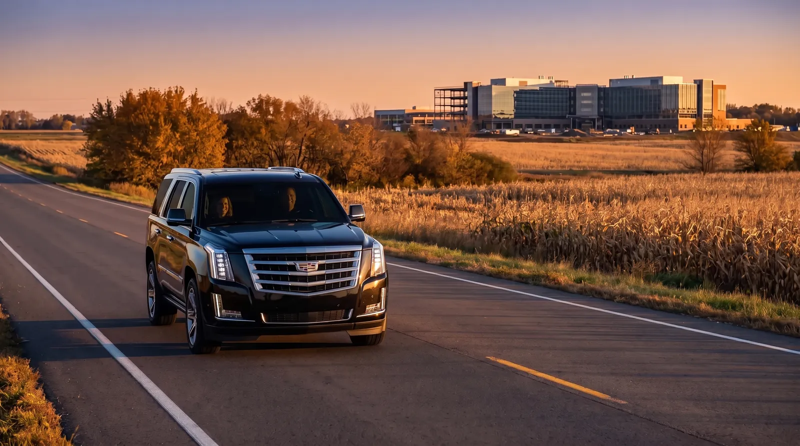 Black Cadillac Escalade on a rural Minnesota highway through autumn farmland at sunrise